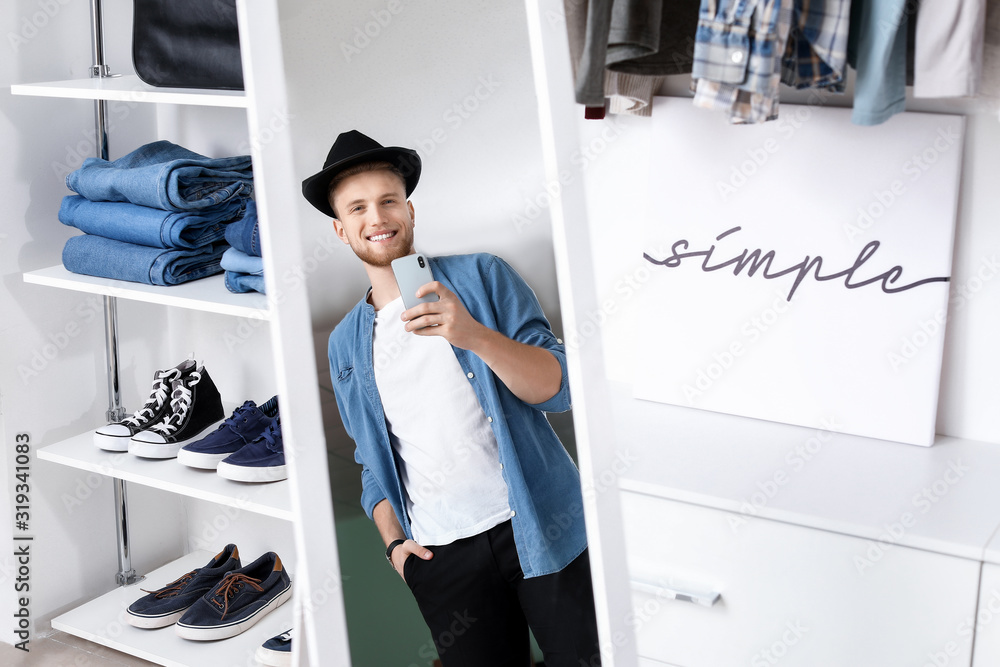 Handsome man trying on stylish clothes in dressing room