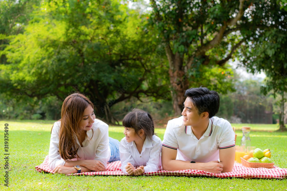 Asian teen family happy holiday picnic moment in the park with father, mother and daughter lying on 