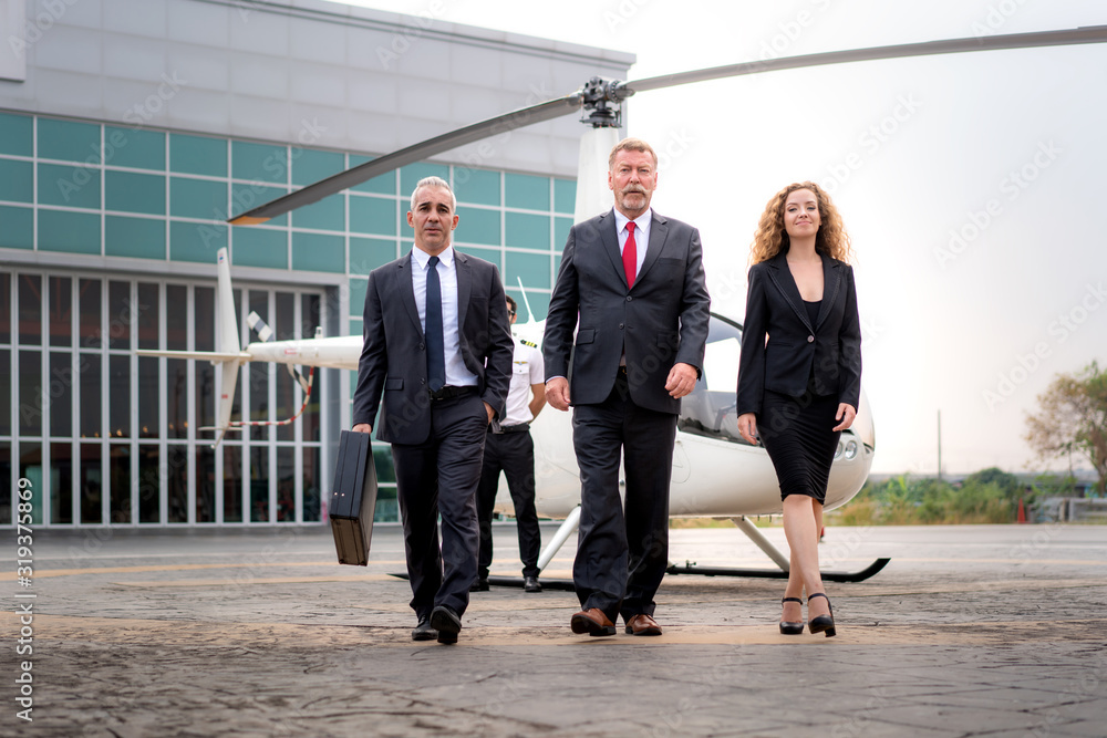 Three Businessman and businesswoman manager with Briefcase walking from helicopter when he arrive de