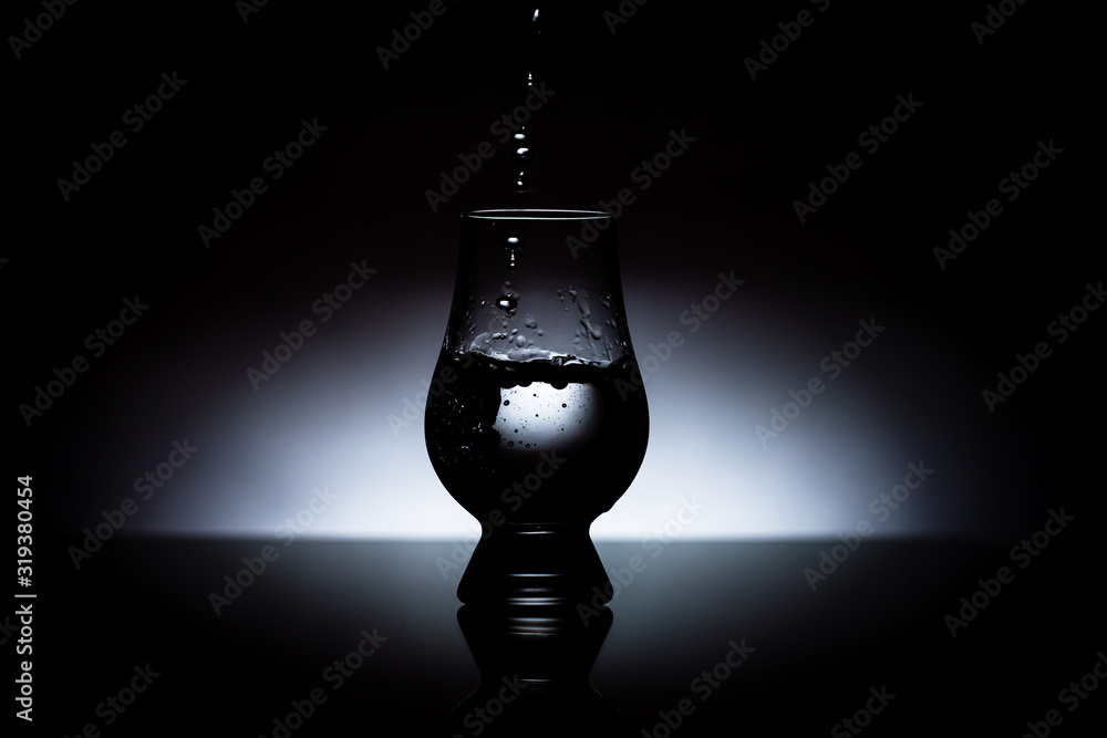 Water poured into a glass - isolated on black