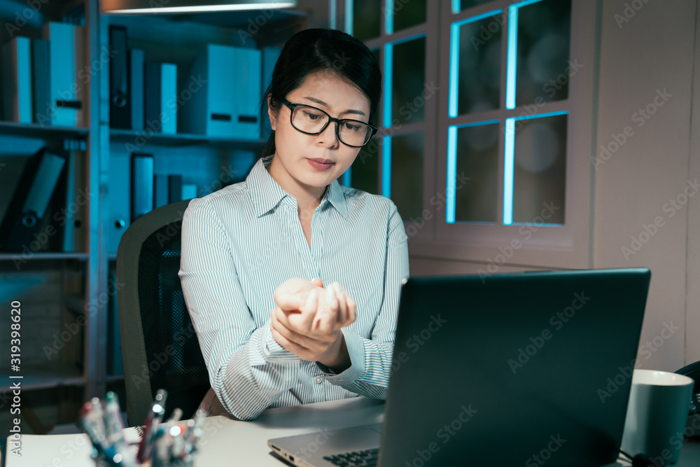 elegant asian chinese businesswoman holding her wrist pain from long time using laptop computer typi