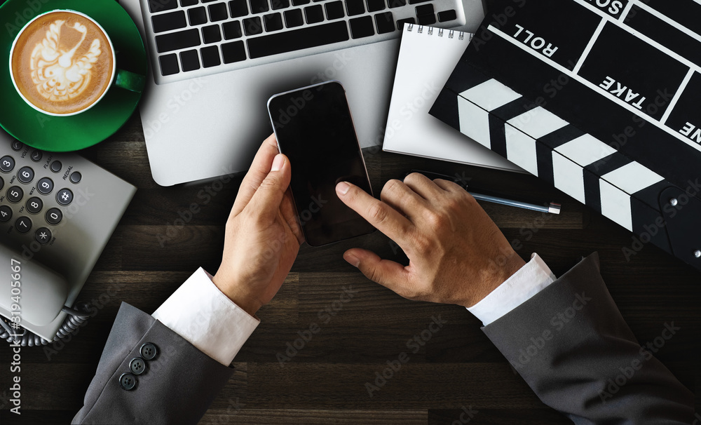 Woman hands typing laptop with office stuff with Movie clapper, laptop, smartphone, tablet, coffee c