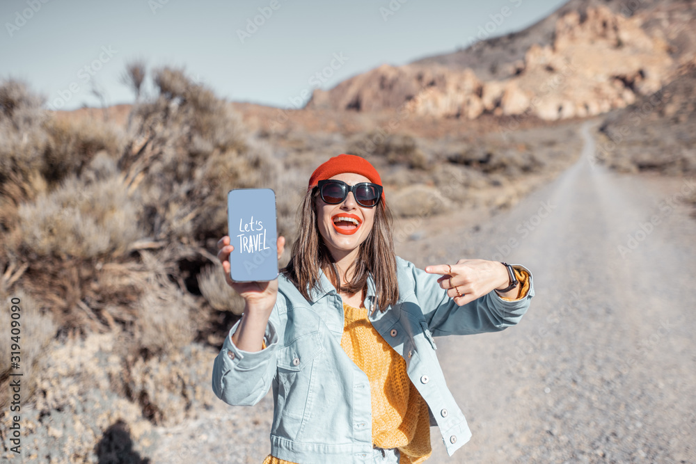 Young and happy woman showing smartphone with a drawing on a topic of travel during a trip on the de