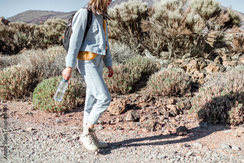 Young woman traveling on the volcano valley, walking desert road. Image focused on the background