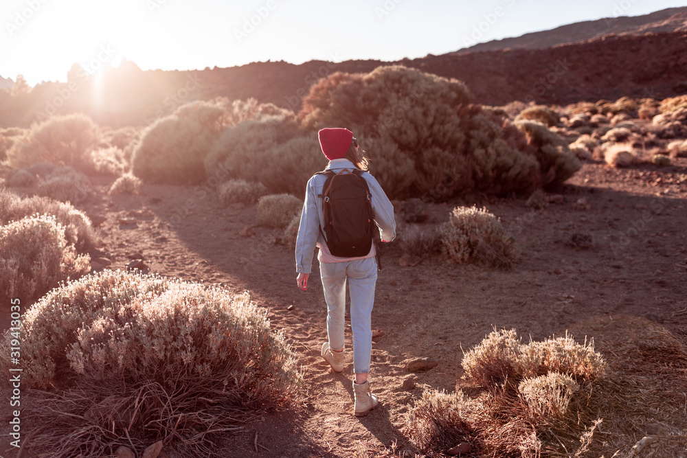 Landscape view on a beautiful volcanic valley with woman hiking on a sunset. Traveling on Teide nati