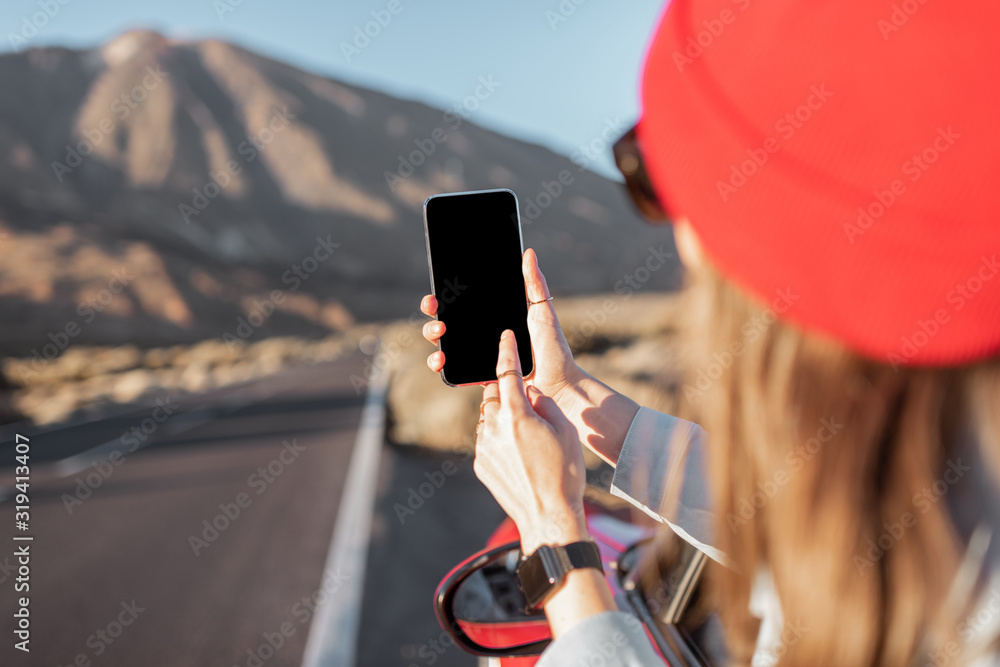 一位女士在火山谷上驾车旅行，探出车窗，用s拍照