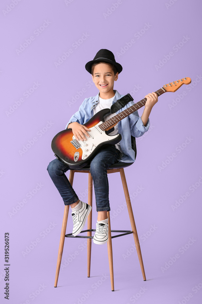 Little boy playing guitar on color background