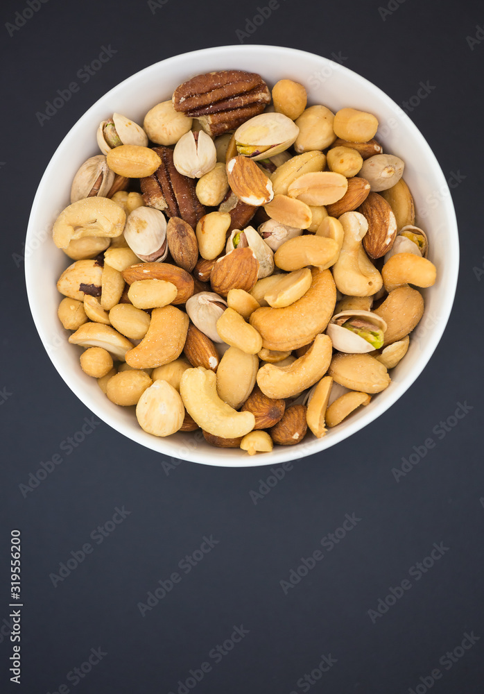 Hazelnut ,Pecan nut, Pistachio nut ,Peanuts nut,Almond nut mixed salt in a wooden plate is Protein f