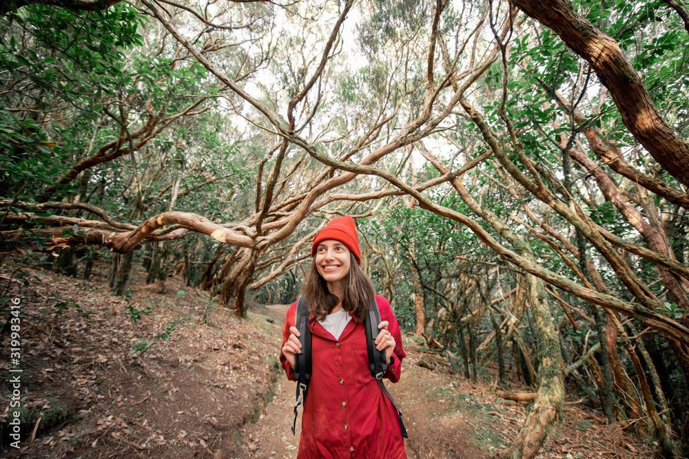 一个快乐女人的画像，穿着红色衬衫，戴着帽子，在美丽的雨林徒步旅行w