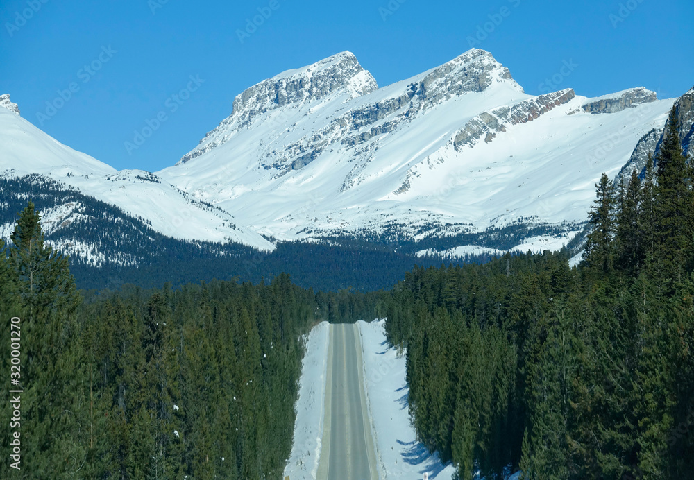 航空航天：白雪皑皑的加拿大落基山脉高耸在空旷的道路上的壮观景色。