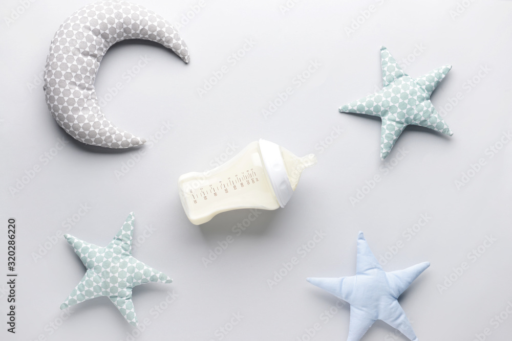 Bottle of milk for baby and toys on white background