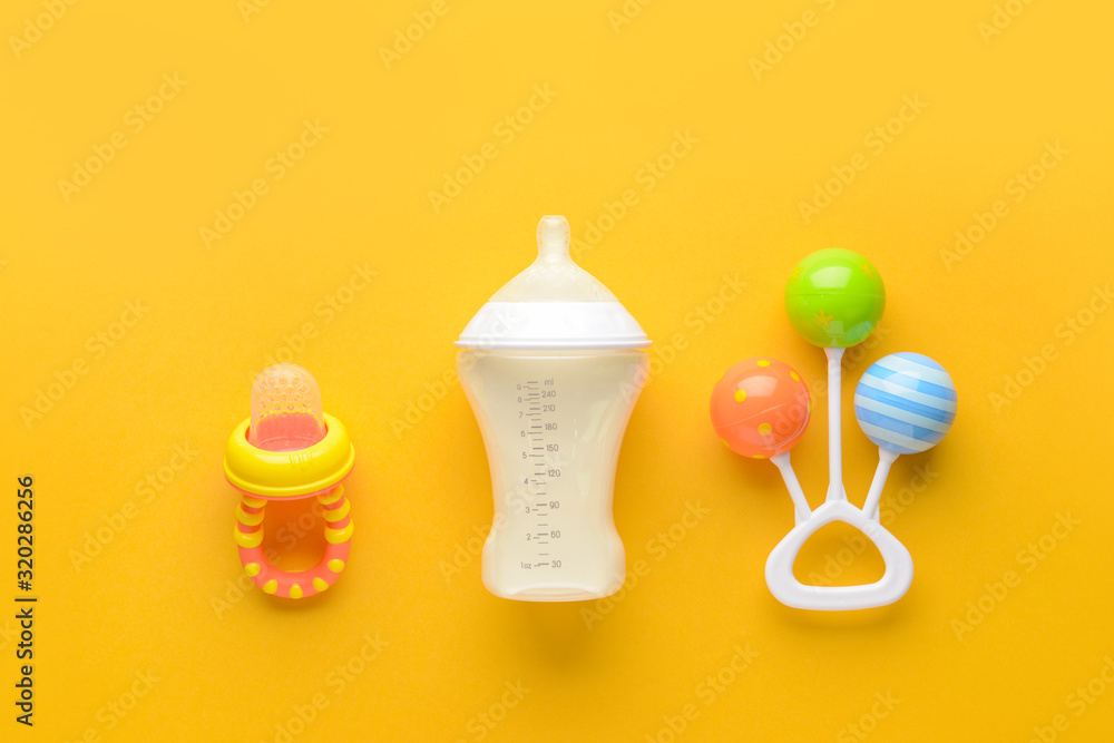 Bottle of milk for baby and toy with pacifier on color background