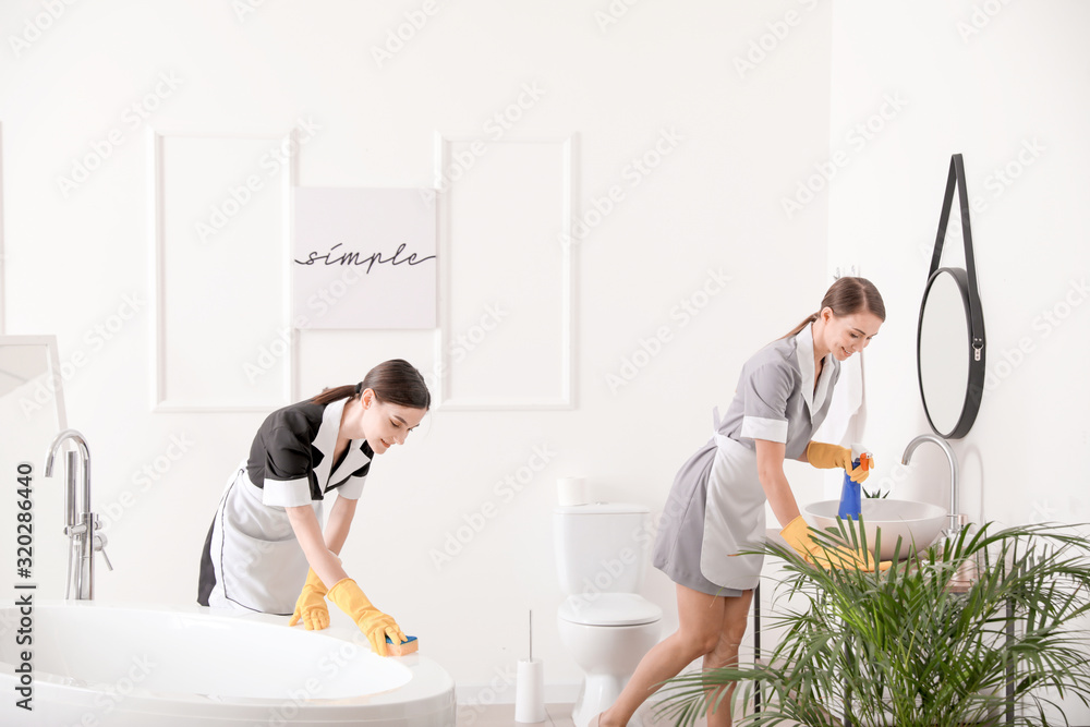 Beautiful chambermaids cleaning hotel bathroom