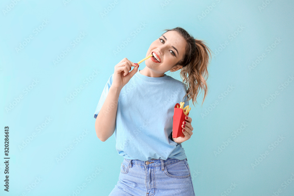 Portrait of beautiful young woman with french fries on color background