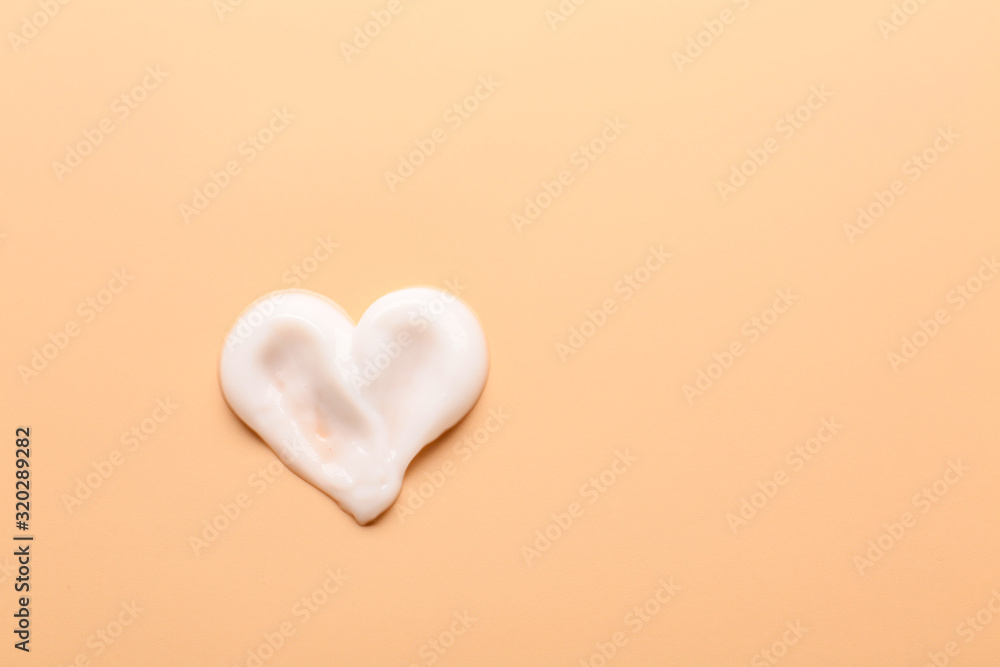 Heart made of cream on color background