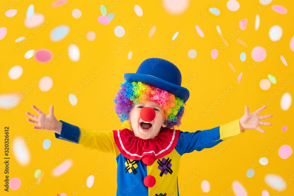 Funny kid clown playing against yellow background