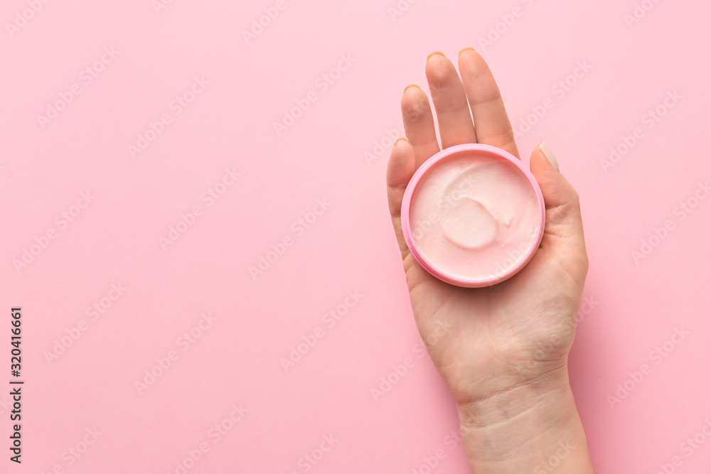 Female hand with jar of cream on color background