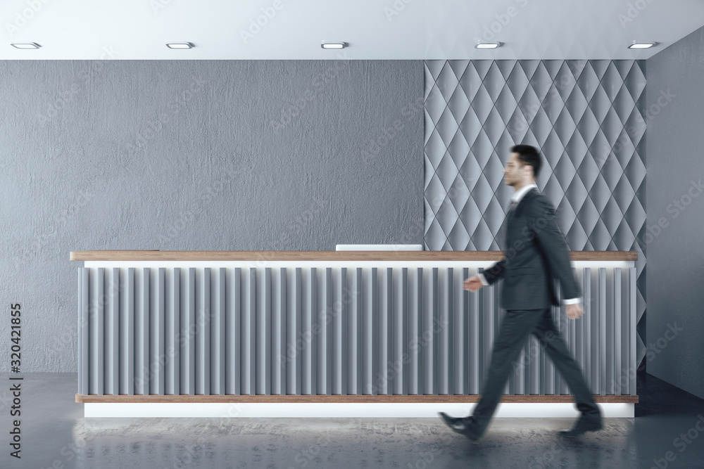 Businessman walking in hotel corridor with reception table.