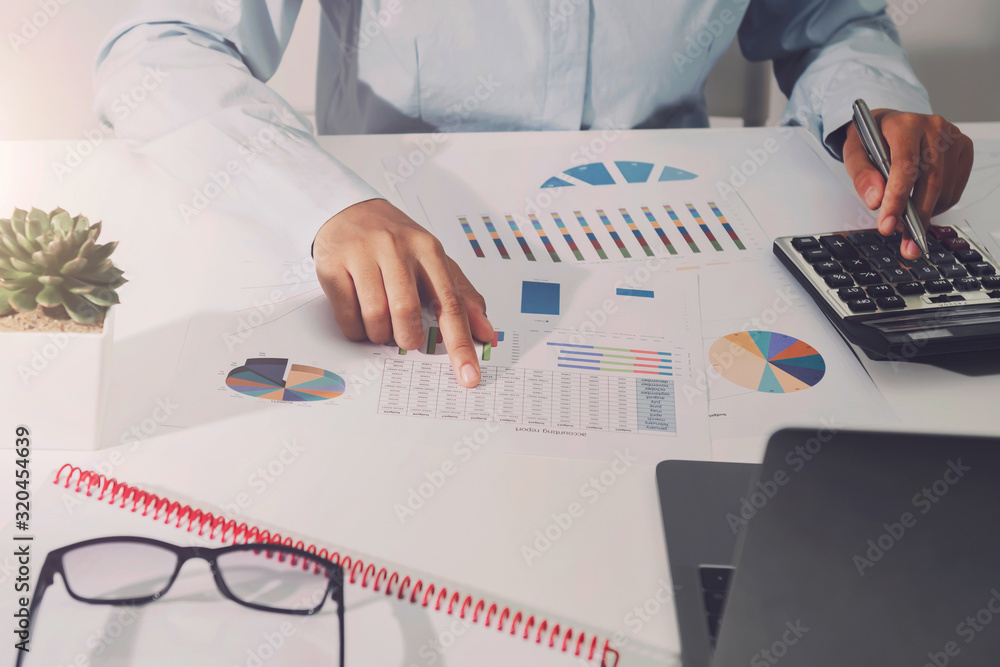 businesswoman working on desk using calculator analyzing finance accounting in office