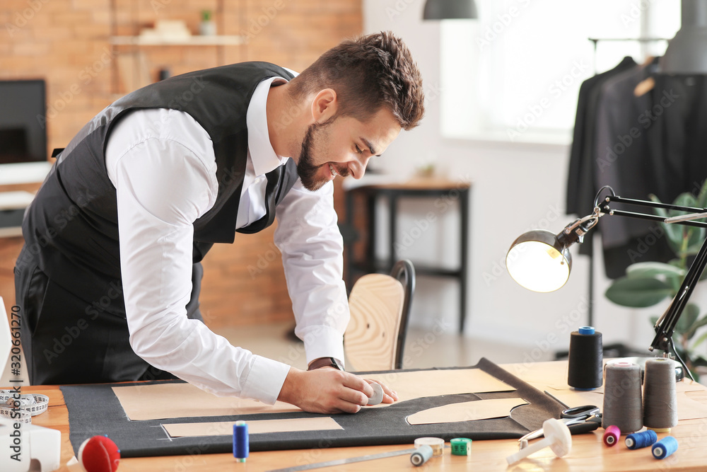 Young tailor working at table in atelier