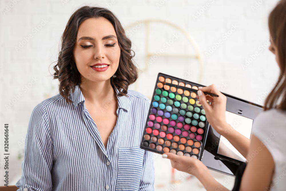 Makeup artist working with beautiful young woman in salon