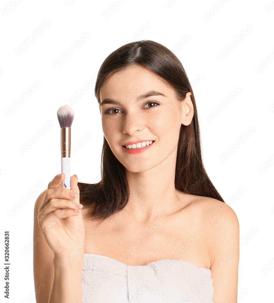 Beautiful young woman with makeup brush on white background