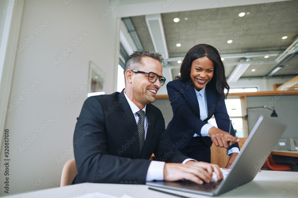 Two smiling businesspeople talking together and working with a l