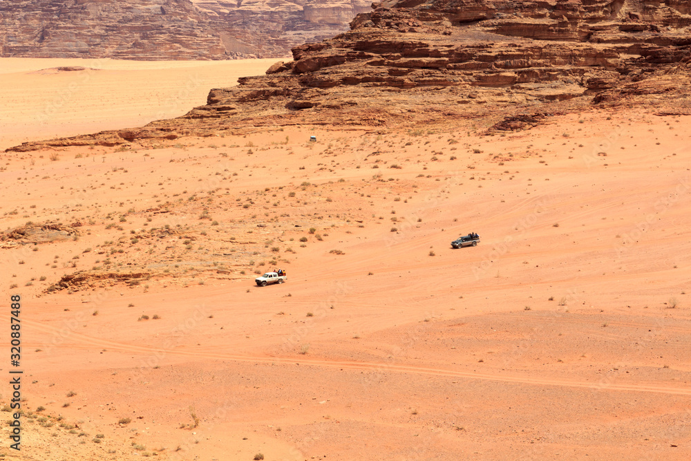 Tourists sitting in pickup truck and enjoying a guided tour in Wadi Rum desert, Jordan