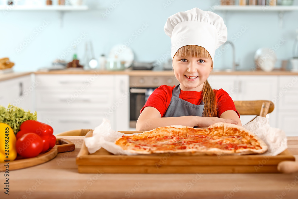 Cute little chef cooking pizza in kitchen