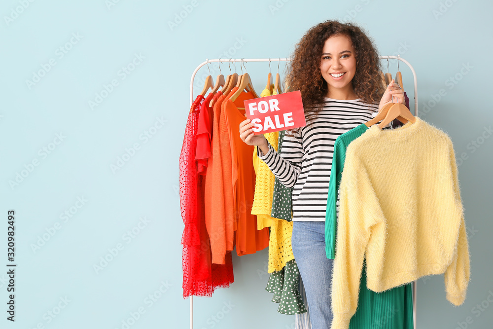 African-American stylist near rack with modern clothes