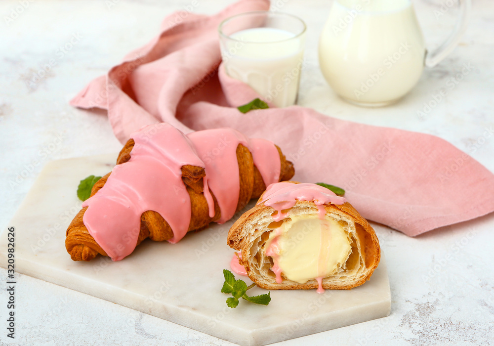 Board with tasty sweet croissants and milk on white background