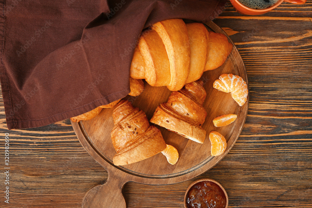 Board with tasty sweet croissants and jam on wooden table