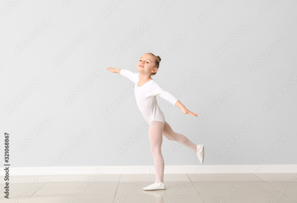 Cute little ballerina against light wall