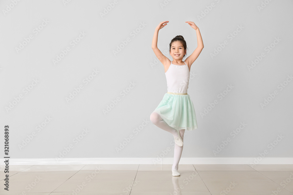 Cute little ballerina against light wall