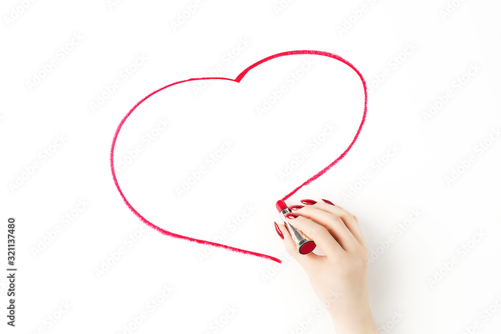 Beautiful female hand with trendy red manicure drawing heart with vibrant red lipstick on white back