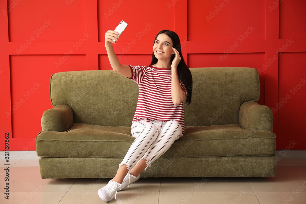 Young woman taking selfie while sitting on sofa at home