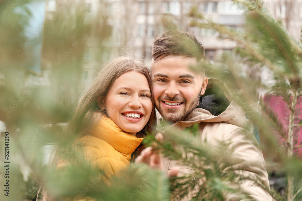 Young couple buying Christmas tree at the market