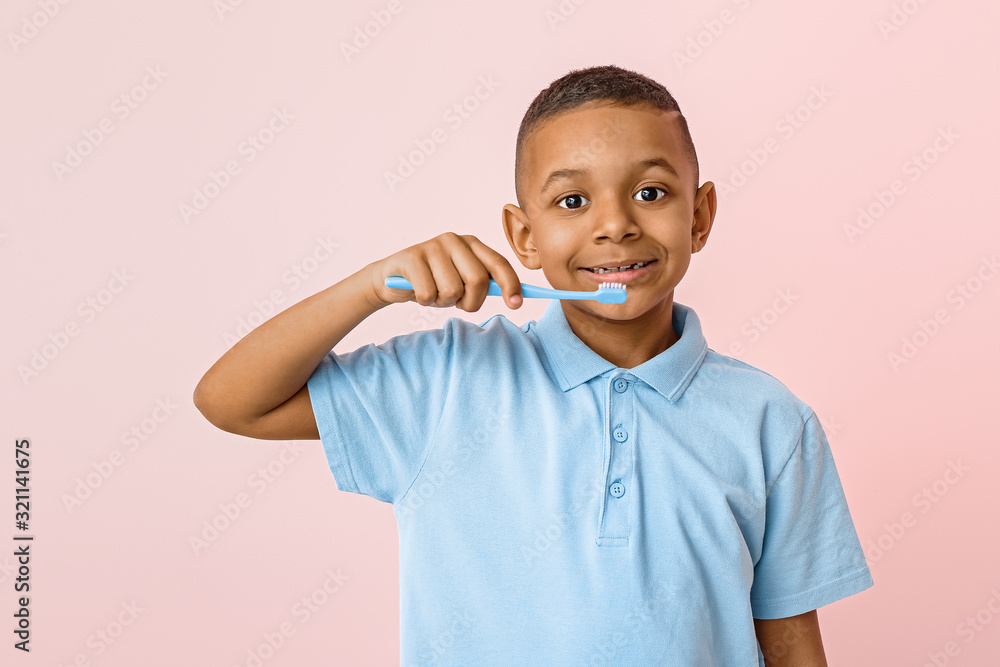 Little African-American boy with tooth brush on color background