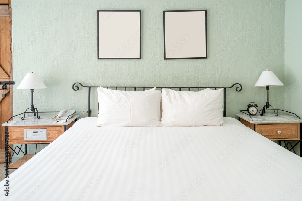 Bright and brand new interior of european bedroom with white lamp on wooden table and white blanket 