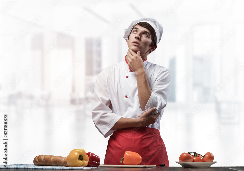 Young male chef standing with folded arms