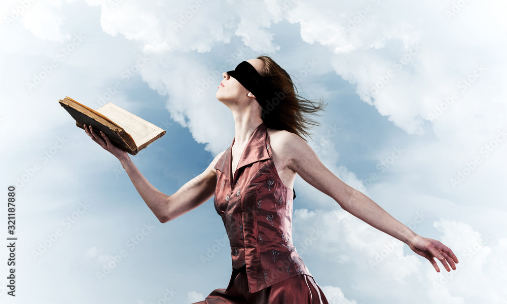 Girl against cloudy sky with opened book in palm as idea for knowledge