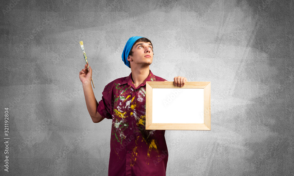 Young handsome painter artist holding paintbrush