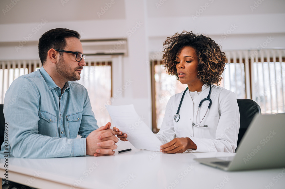 Portrait of a young doctor discussing with a patient.