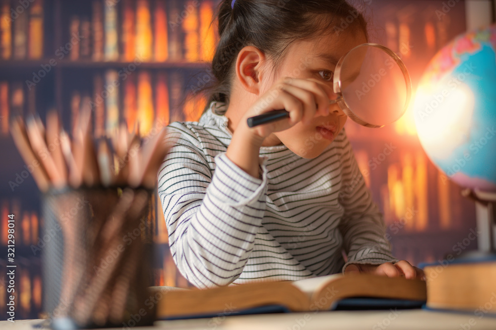 勤劳的亚洲小女孩坐在室内的桌子旁。孩子在家学习