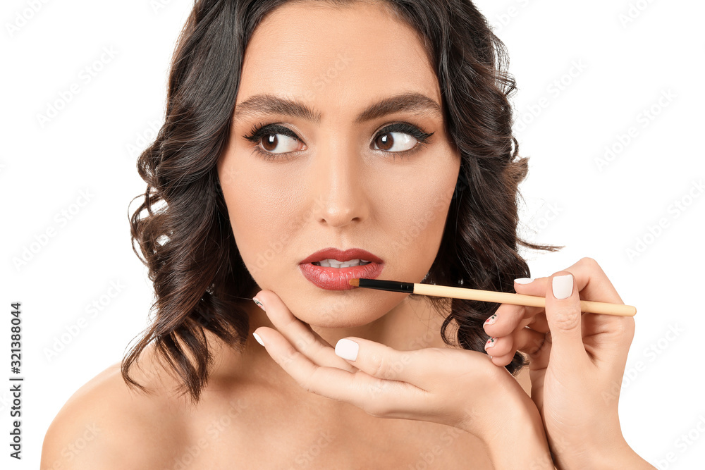 Makeup artist working with beautiful young woman on white background