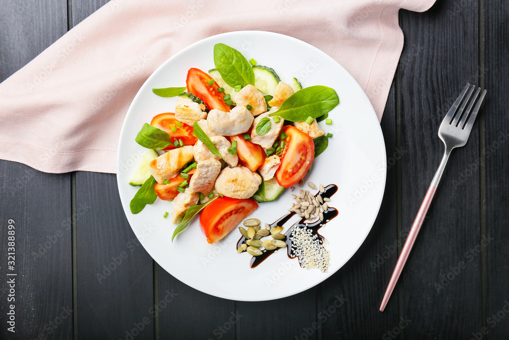 Plate with tasty chicken salad on table