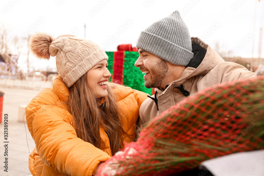 Happy young couple after buying Christmas tree at the market