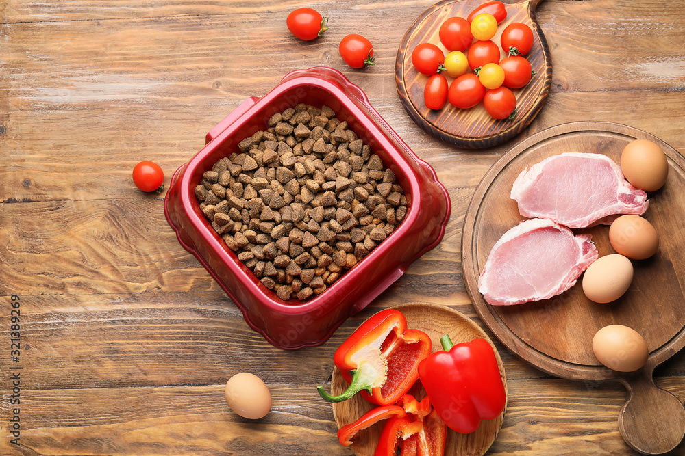 Composition with dry pet food and natural products on wooden background