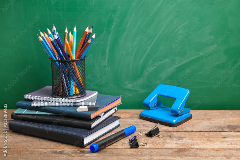 Set of school supplies on table near blackboard