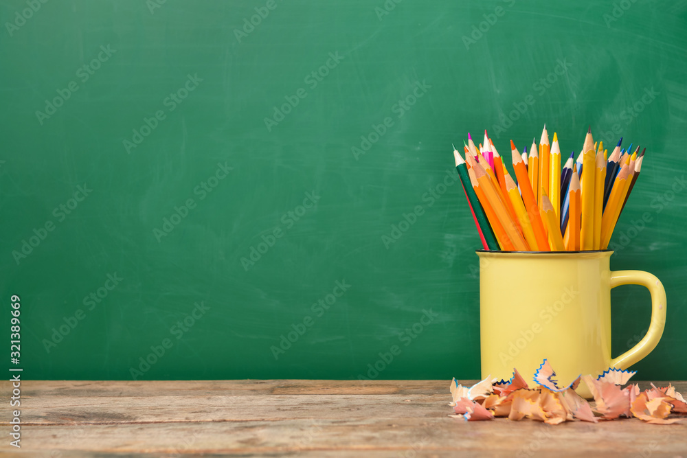 Many pencils on table near blackboard